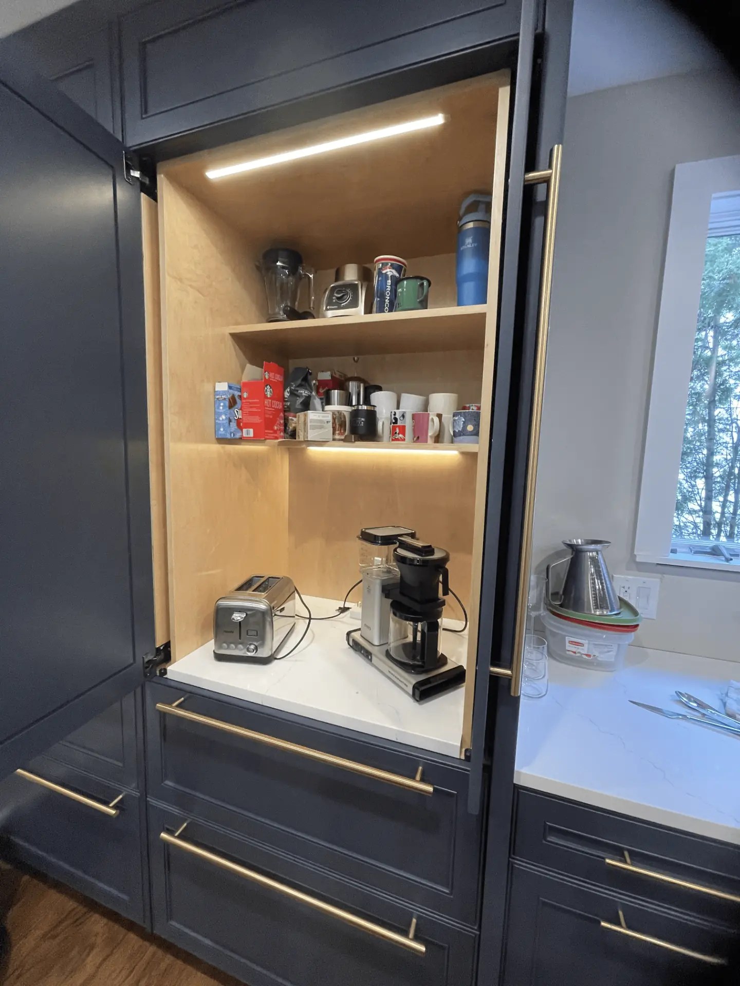 Built-in cabinet with a lit coffee and appliance station on open shelving