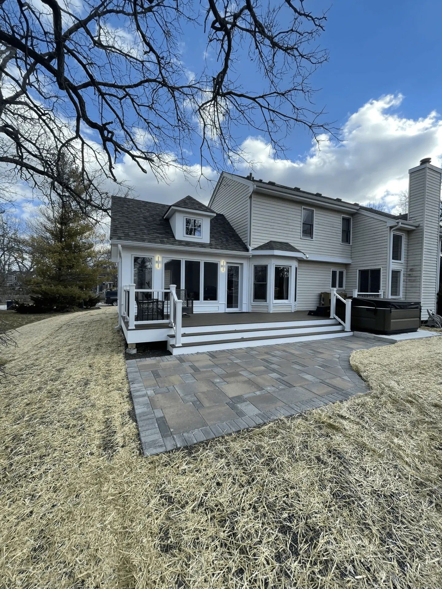 Finished rear addition with a covered porch, composite deck, and new paver patio
