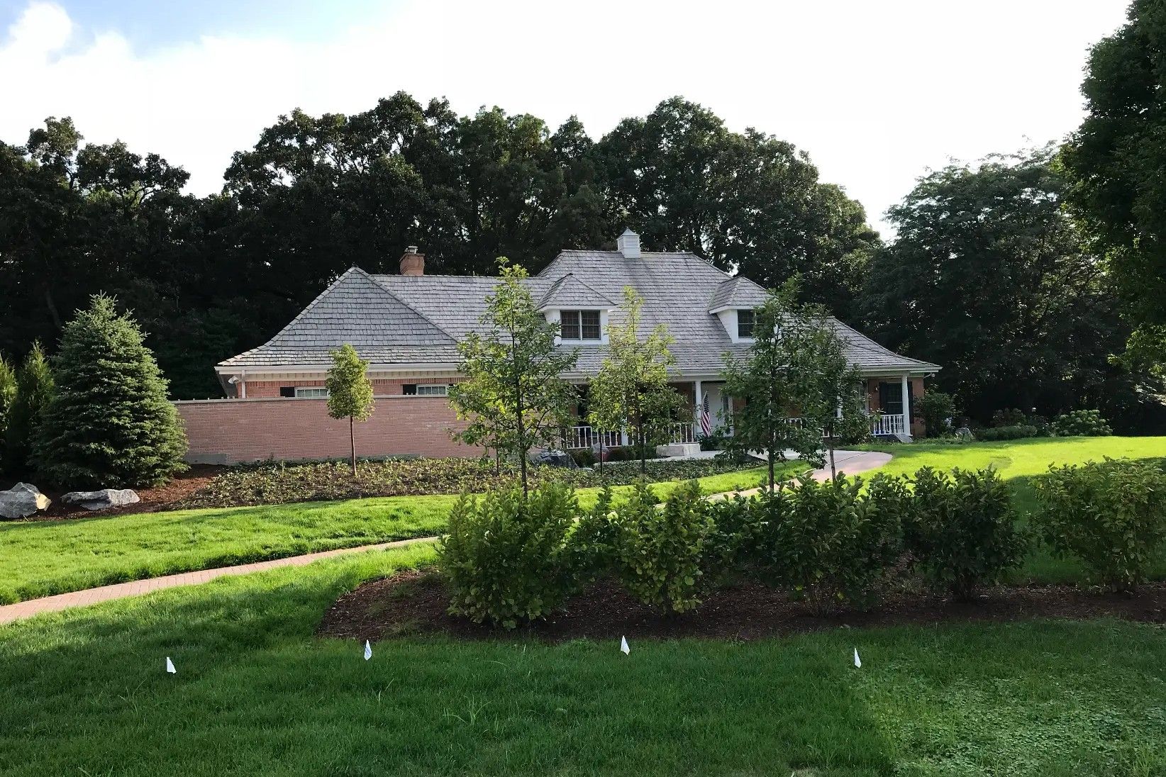 Finished brick home with a completed roof, landscaped lawn, and brick walkway