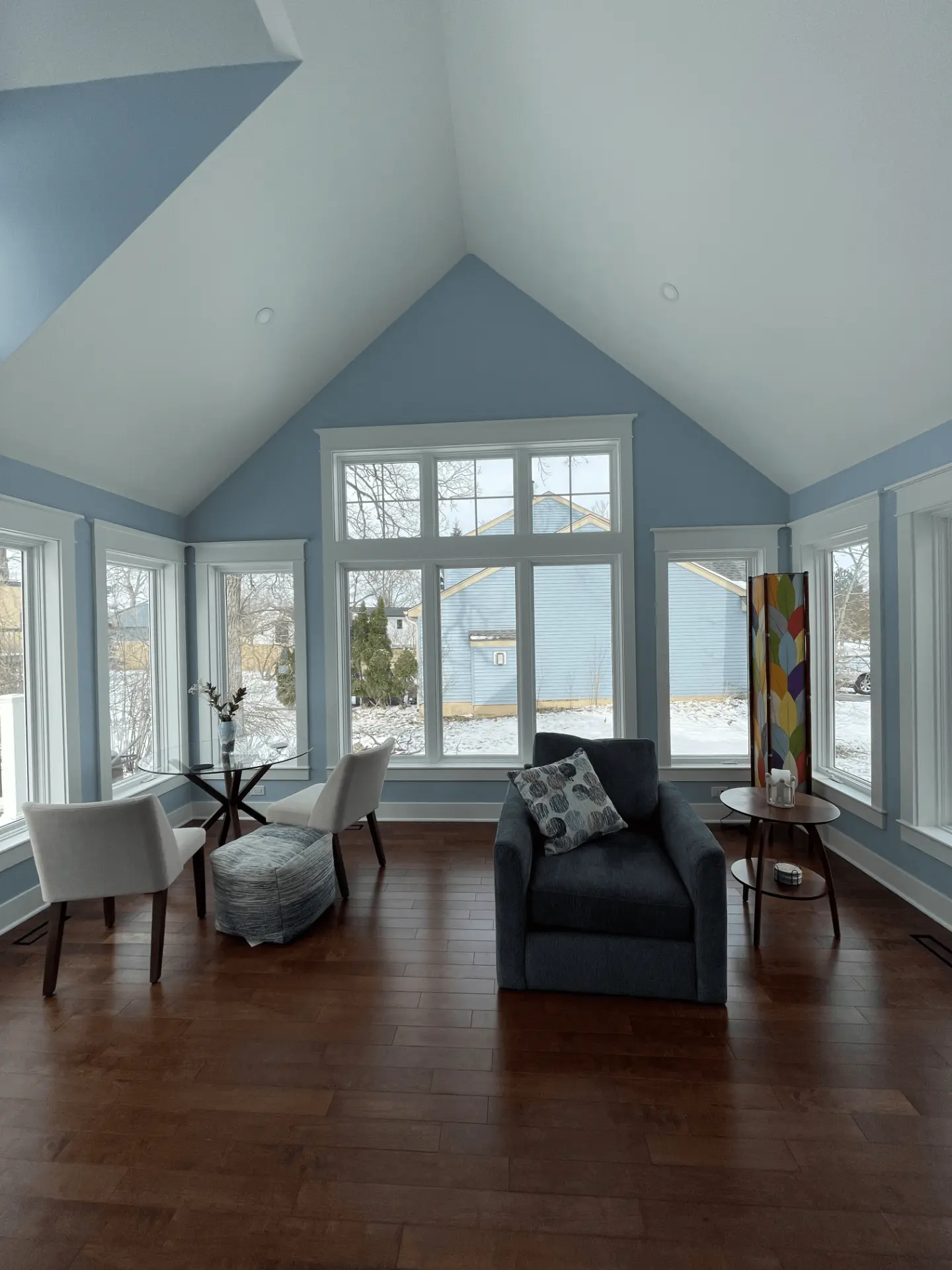 The finished vaulted family room in pale blue and hardwood under a tall ceiling