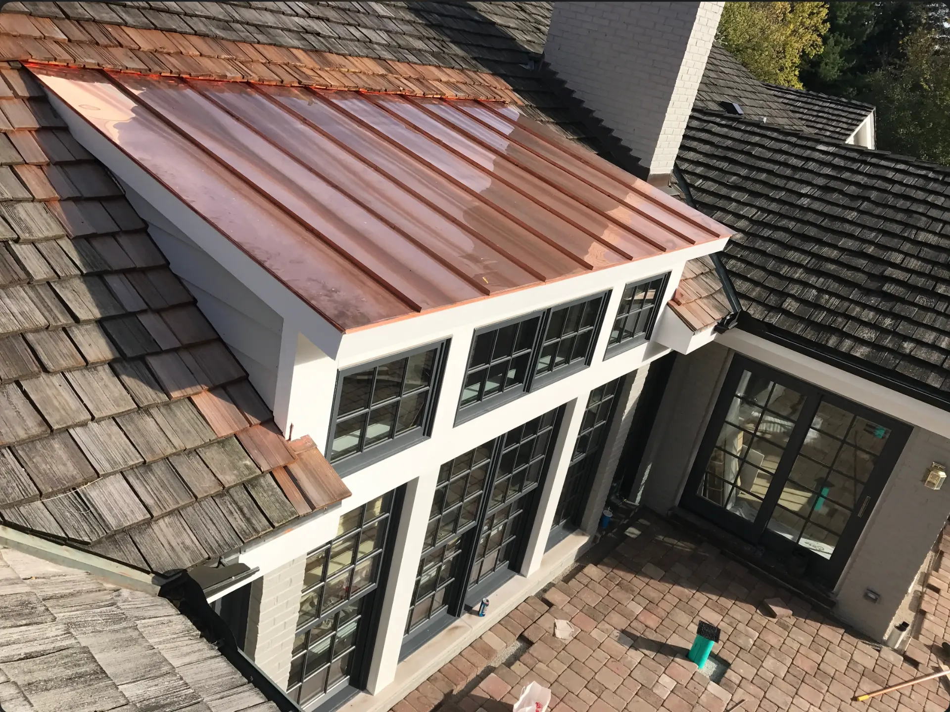 Overhead view of the finished addition with copper standing-seam panels and divided-light windows