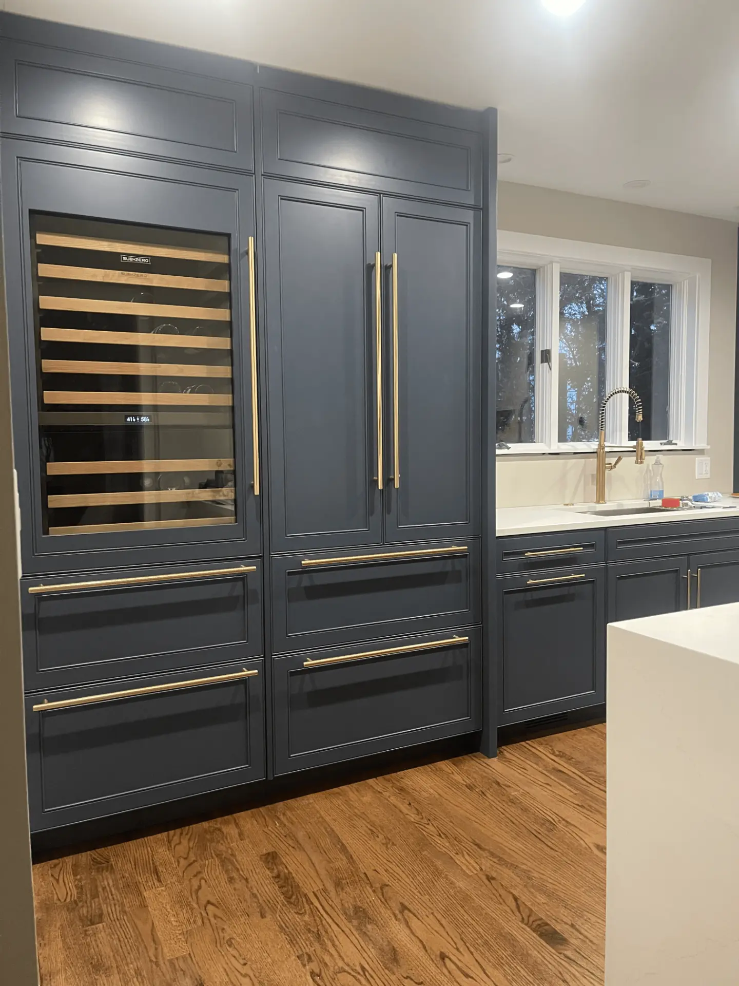 Tall custom navy cabinetry with a wine storage column and brass hardware